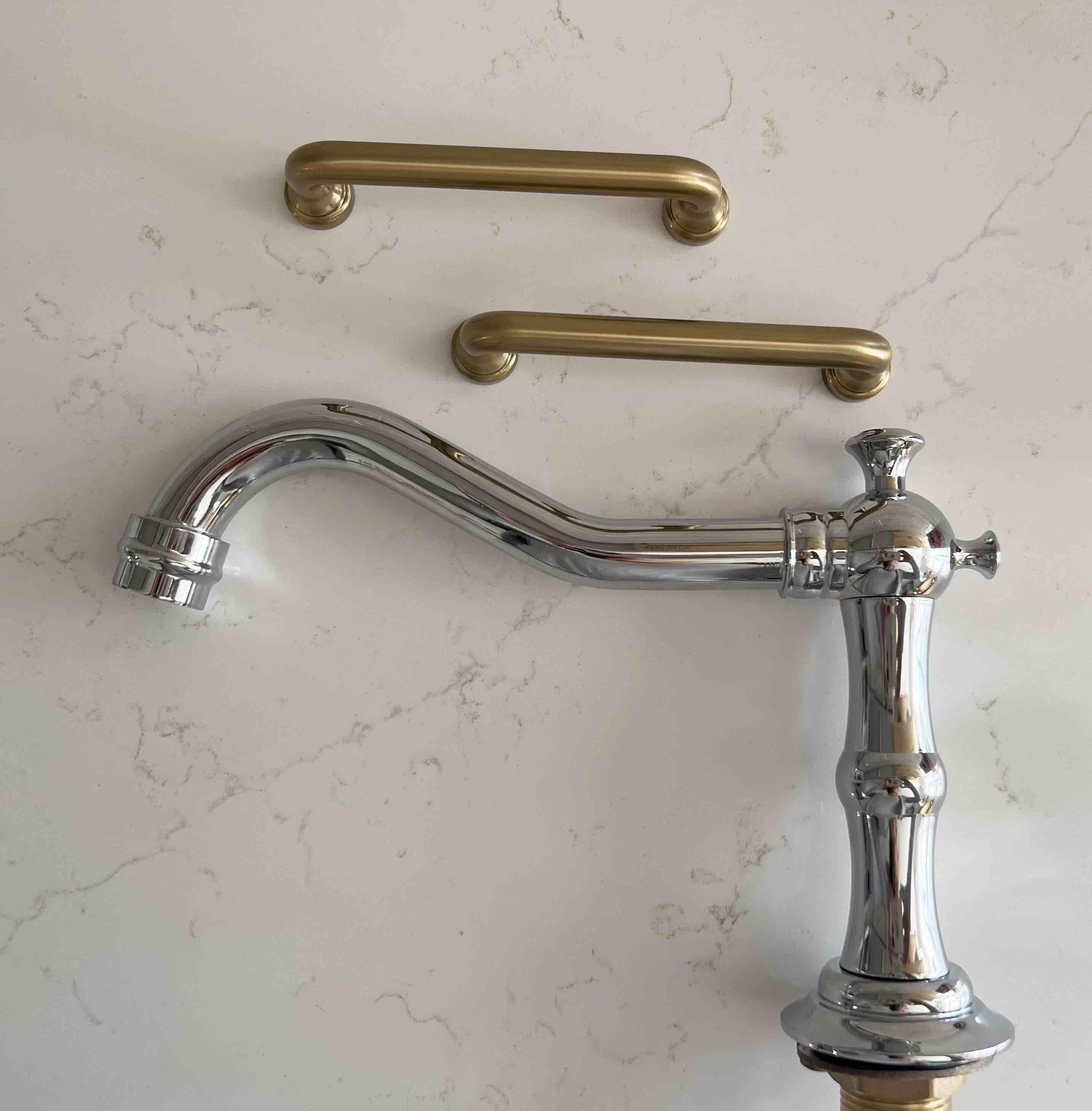 Antique brass cabinet pull hardware on a marble counter with shiny polished chrome vintage heritage faucet